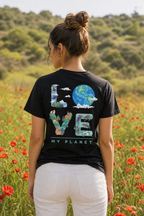 אישה לובשת חולצת כותנה אורגנית עם הדפס LOVE MY PLANET על הגב, עומדת בשדה כלניות אדומות בישראל — אדם וטבע
