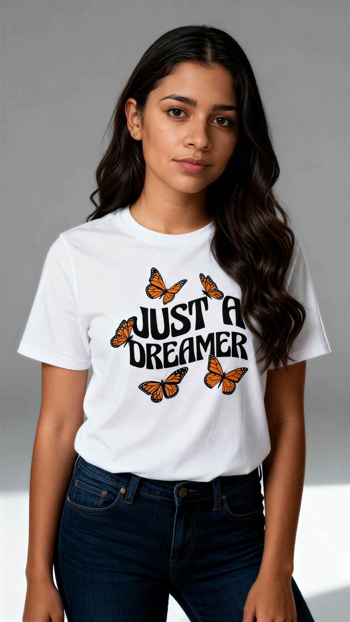תקריב של הדפס פרפרים כתומים וכיתוב Just a Dreamer על חולצת טי לבנה
